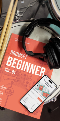 Schlagzeug-Lehrbuch „Drumset Beginner“ mit Kopfhörer und Smartphone auf einer Snare